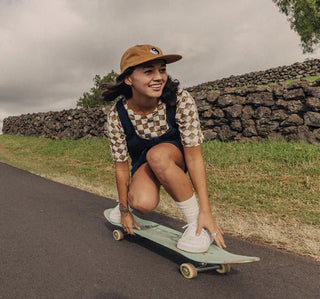 girl on a longboard riding down a street in the countryside