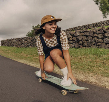 girl on a longboard riding down a street in the countryside